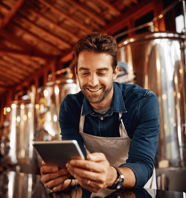 Cervejeiro usando um tablet entre tanques de produção